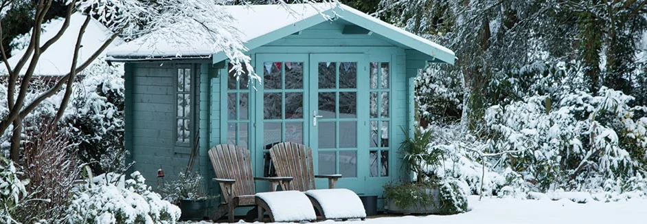 Verschneiter Garten mit blauem Gartenhaus